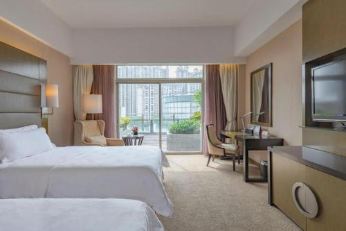 a hotel room with two beds and a television at Jiaxin Conifer Hotel Shunde in Shunde