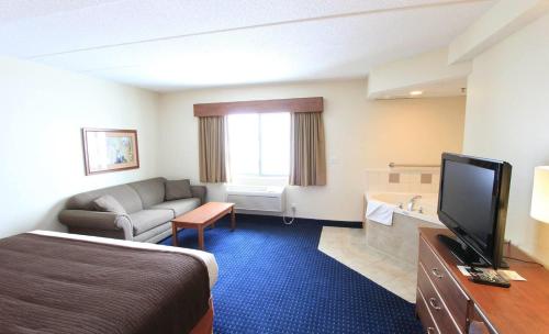 a hotel room with a bed and a couch and a television at AmericInn by Wyndham Cedar Rapids Airport in Cedar Rapids