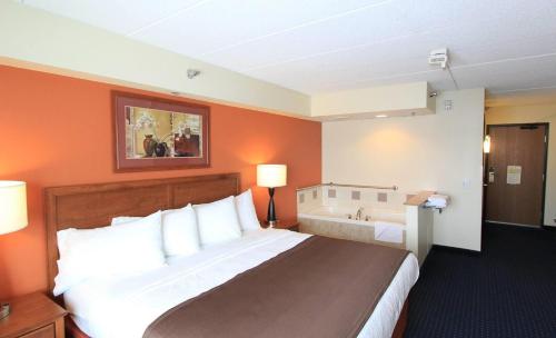 a hotel room with a large bed and a bathroom at AmericInn by Wyndham Cedar Rapids Airport in Cedar Rapids
