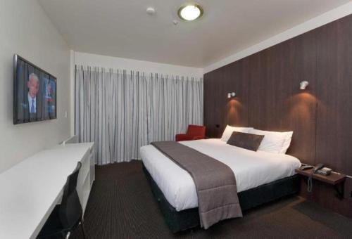 a hotel room with a large white bed and a television at The Riccarton Hotel in Christchurch