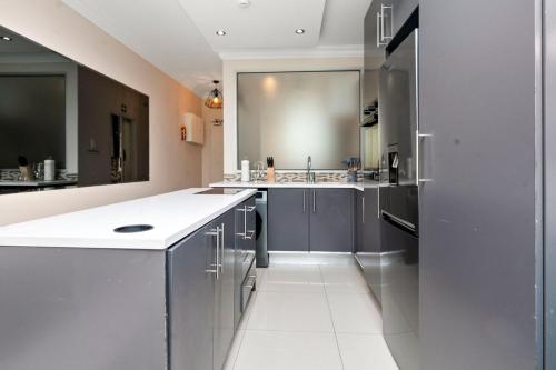 a kitchen with gray cabinets and a white floor at CityPad 1 Bed w Balcony 5 mins to V&A, CTICC in Cape Town