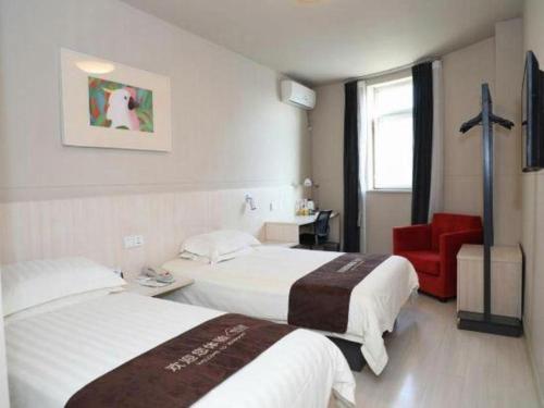 a hotel room with two beds and a red chair at Jinjiang Inn Changchun Xi An Avenue Branch in Changchun