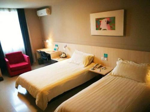 a hotel room with two beds and a red chair at Jinjiang Inn Changchun Xi An Avenue Branch in Changchun