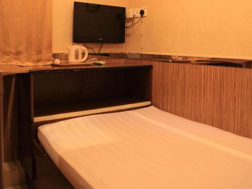 a bedroom with a bed with a tv on top at New Mong Kok Guest House in Hong Kong