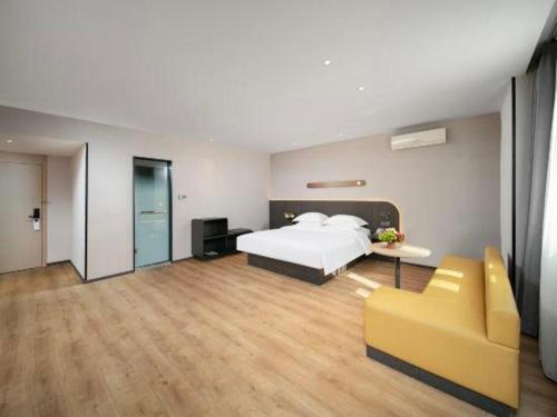 a bedroom with a bed and a yellow couch at Jinjiang Inn Changchun Xi An Avenue Branch in Changchun