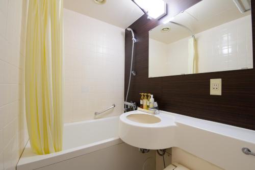 a bathroom with a sink and a mirror and a tub at Chisun Hotel Utsunomiya in Utsunomiya