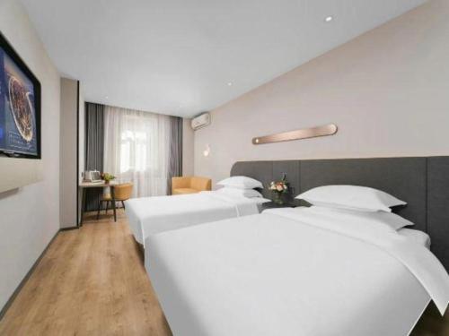 a hotel room with two beds and a table at Jinjiang Inn Changchun Xi An Avenue Branch in Changchun