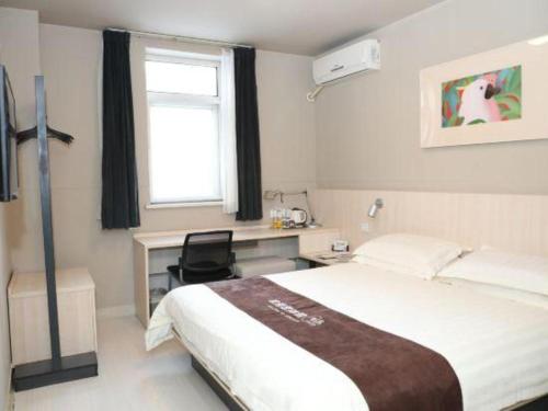 a bedroom with a bed and a desk and a window at Jinjiang Inn Changchun Xi An Avenue Branch in Changchun