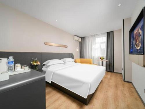 a bedroom with a large white bed and a desk at Jinjiang Inn Changchun Xi An Avenue Branch in Changchun