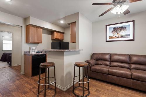 a living room with a couch and a kitchen at Eagle's Den Suites Big Spring a Travelodge by Wyndham in Big Spring