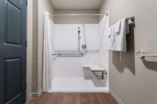 a white bathroom with a shower and a sink at Eagle's Den Suites Big Spring a Travelodge by Wyndham in Big Spring