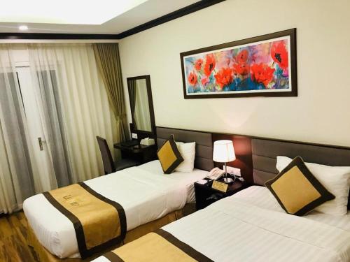 a hotel room with two beds and a painting on the wall at Lenid Hotel Tho Nhuom in Hanoi