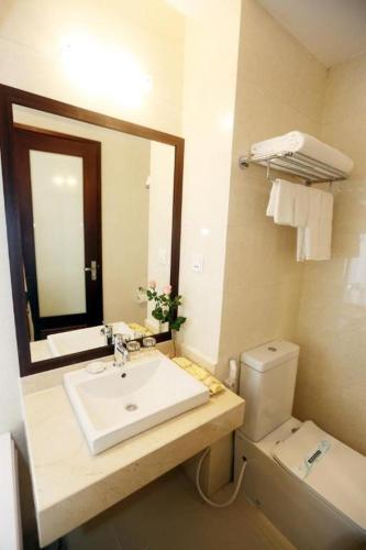 a bathroom with a sink and a toilet and a mirror at Lenid Hotel Tho Nhuom in Hanoi