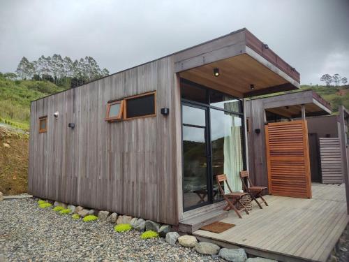 a small wooden house with a deck and a chair at Alawa Kundasang in Kundasang