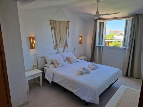 a bedroom with a white bed and a window at Apartamento Calan Forcat in Ciutadella