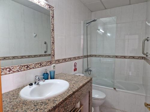 a bathroom with a sink and a shower and a toilet at Apartamento Calan Forcat in Ciutadella