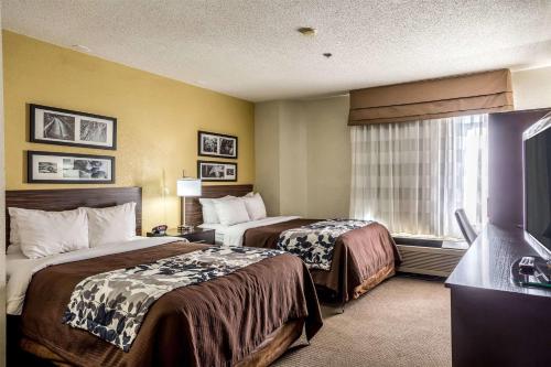 a hotel room with two beds and a television at Wingate by Wyndham Owensboro in Owensboro