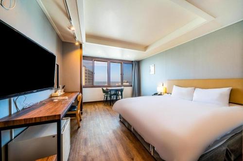 a hotel room with a large white bed and a desk at Check Inn Hotel in Jeju