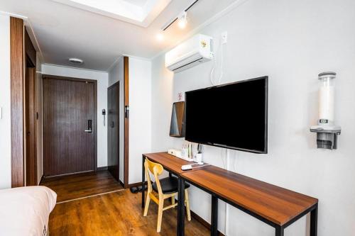 a bedroom with a desk with a television on a wall at Check Inn Hotel in Jeju
