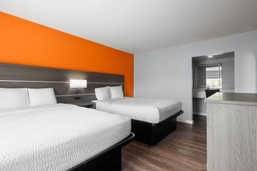 a hotel room with two beds and an orange wall at Baymont by Wyndham Salisbury MD in Salisbury
