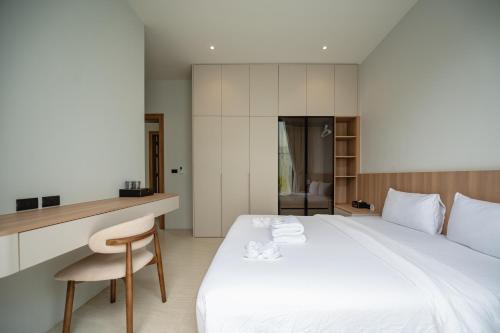 a bedroom with a large white bed and a chair at Mouana Residence Song Khun Chalong 5-bedroom Pool Villa 89-11 in Chalong 