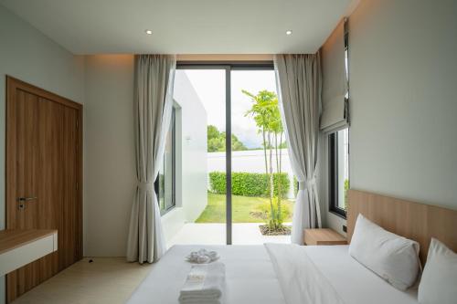 a bedroom with a bed and a large window at Mouana Residence Song Khun Chalong 5-bedroom Pool Villa 89-11 in Chalong 