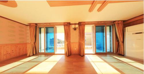 an empty living room with glass doors and windows at Cable Car Pension in Yeosu