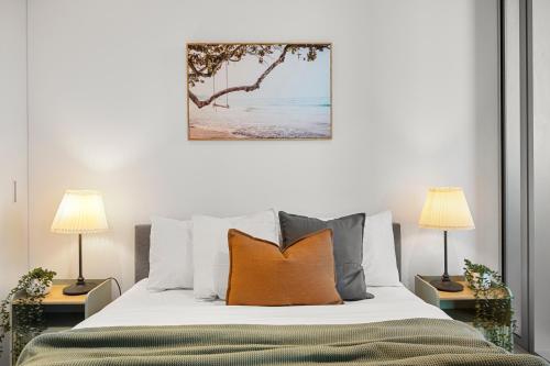 a bedroom with a bed with pillows and two lamps at Urban Gem 2BR Apartment in CBD in Melbourne
