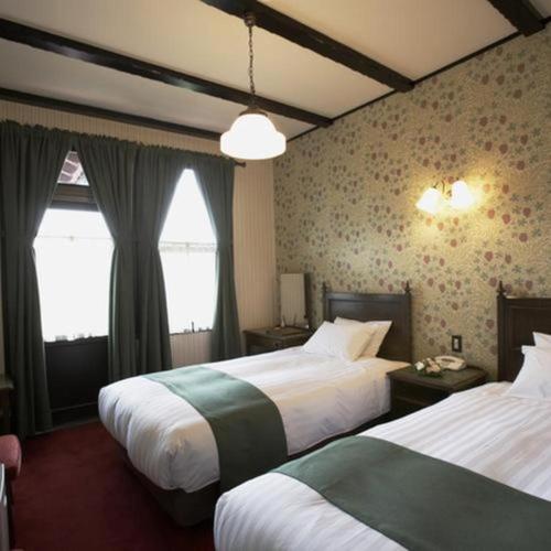a hotel room with two beds and a window at Unzen Kanko Hotel in Unzen