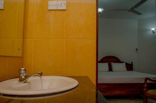a bathroom with a sink and a bedroom with a bed at New King well resort and guest house in Ahangama