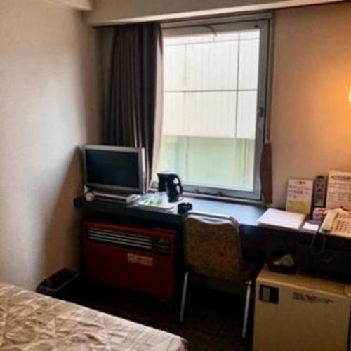 a bedroom with a desk with a computer and a window at Shizuoka UI Hotel in Shizuoka