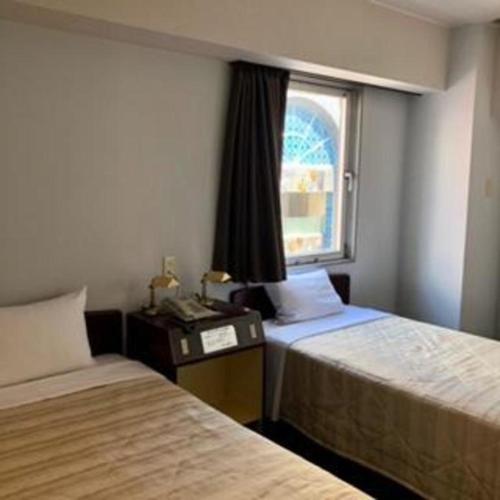 a hotel room with two beds and a window at Shizuoka UI Hotel in Shizuoka