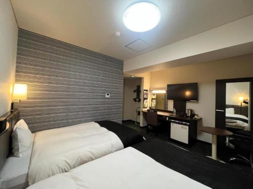 a hotel room with two beds and a desk at APA Hotel Owari Ichinomiya Eki-mae in Ichinomiya