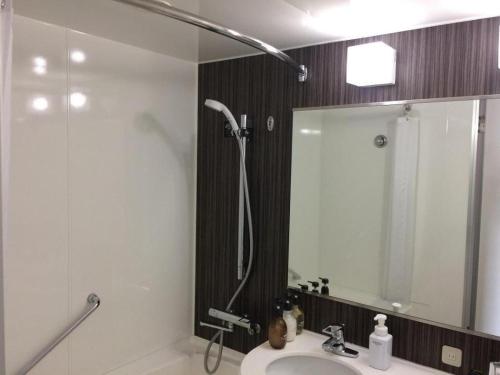 a bathroom with a shower and a sink and a mirror at JR-EAST HOTEL METS NAGAOKA in Nagaoka