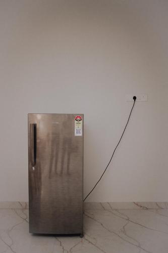 a metallic refrigerator with a cord plugged into a wall at Cozy Nest in Bhubaneshwar