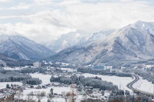 a view of a snowy mountain range with a town at Hotel Alphastar Iwappara in Yuzawa