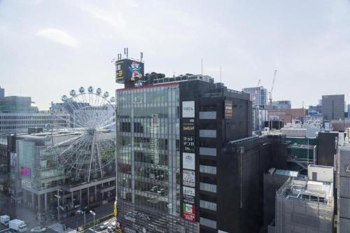 a tall building with a ferris wheel in a city at Hotel Oriental Express Nagoya Sakae in Nagoya