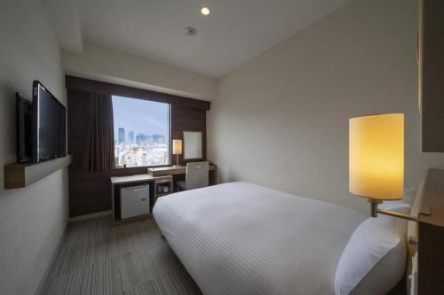 a hotel room with a bed and a window at Hotel Oriental Express Nagoya Sakae in Nagoya