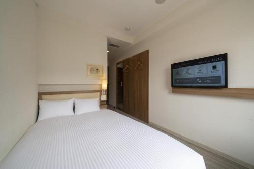 a bedroom with a bed with a tv on the wall at Hotel Oriental Express Nagoya Sakae in Nagoya
