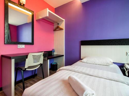 a bedroom with a bed and a desk and a mirror at e Hotel in Melaka