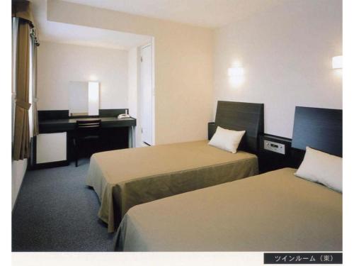 a hotel room with two beds and a desk at Hirata Maple Hotel in Izumo