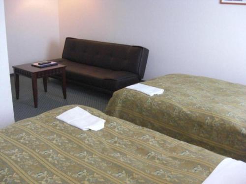 a hotel room with two beds and a couch at Hirata Maple Hotel in Izumo