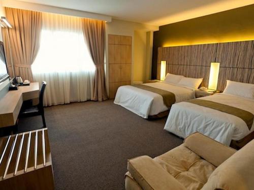 クチンにあるGrand Medallion Hotelのベッド2台とソファがあるホテルの部屋