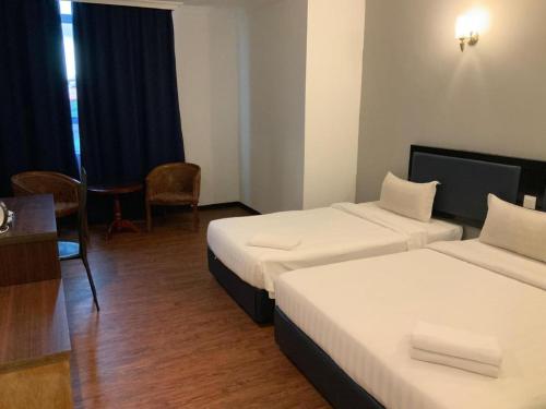 a hotel room with two beds and a table at Disini Hotel in Kampong Sembulan