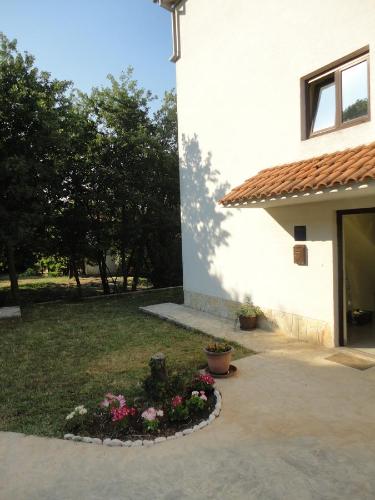 a house with a flower bed in front of a building at Apartments Juretic in Drenje