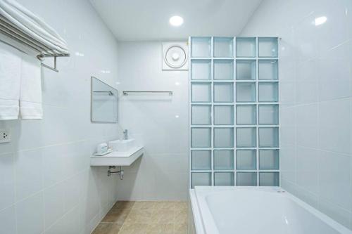 ein weißes Badezimmer mit Badewanne und Waschbecken in der Unterkunft Luxury 6BHK Villa with Private Pool in Pattaya by - OzyStays in Nong Prue