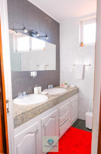 a bathroom with two sinks and a red rug at RUMAH Esposende in Esposende