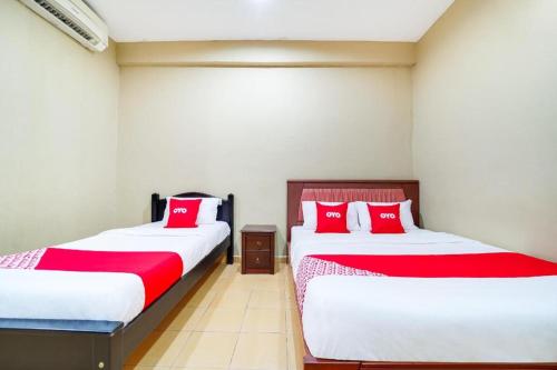 two beds in a room with red and white sheets at OYO 44058 MOTEL SRE BAYAM in Lunas