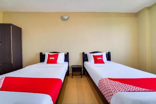 two beds in a room with red and white pillows at OYO 44058 MOTEL SRE BAYAM in Lunas