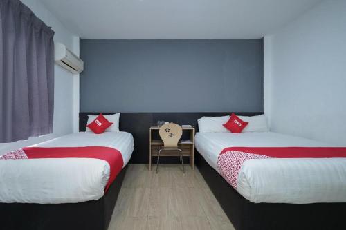 a bedroom with two beds and a desk with a chair at OYO 90106 Sindbad Hotel in Kuala Lumpur